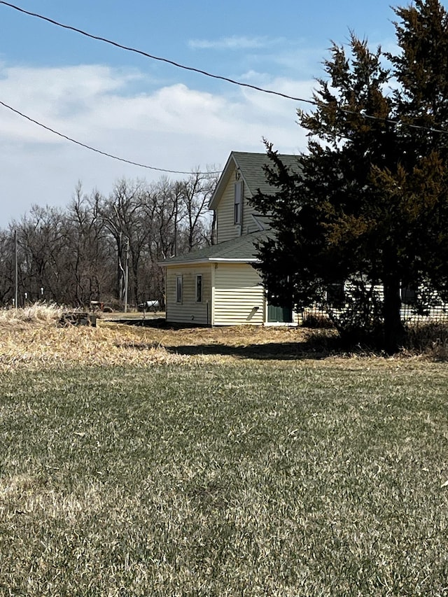 view of property exterior featuring a lawn and a shingled roof