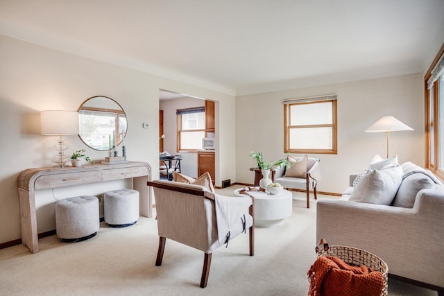 living area featuring light carpet and baseboards