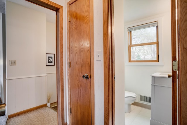 bathroom with vanity, toilet, a wainscoted wall, and visible vents