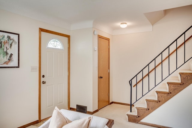 foyer featuring carpet flooring, visible vents, baseboards, and stairway