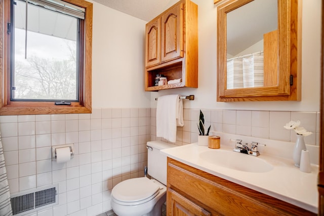 full bathroom featuring tile walls, toilet, wainscoting, visible vents, and vanity