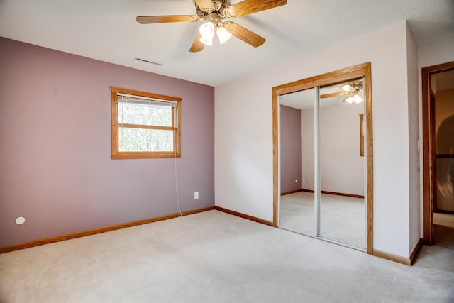 unfurnished bedroom with a closet, baseboards, ceiling fan, visible vents, and light carpet