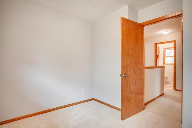 spare room featuring light carpet and baseboards