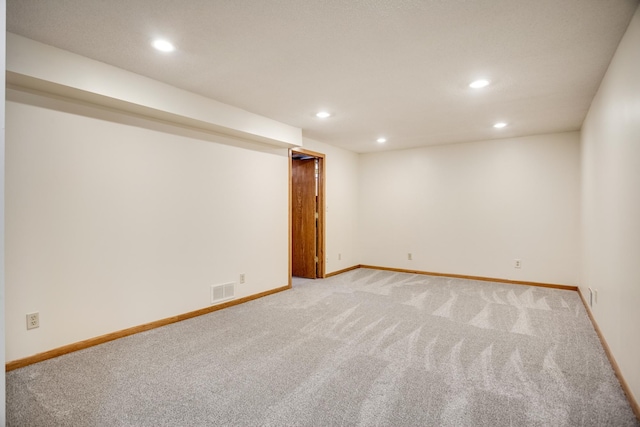finished below grade area featuring light colored carpet, baseboards, visible vents, and recessed lighting