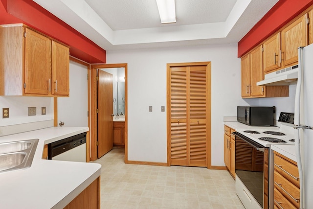 kitchen with under cabinet range hood, light countertops, white appliances, and a raised ceiling
