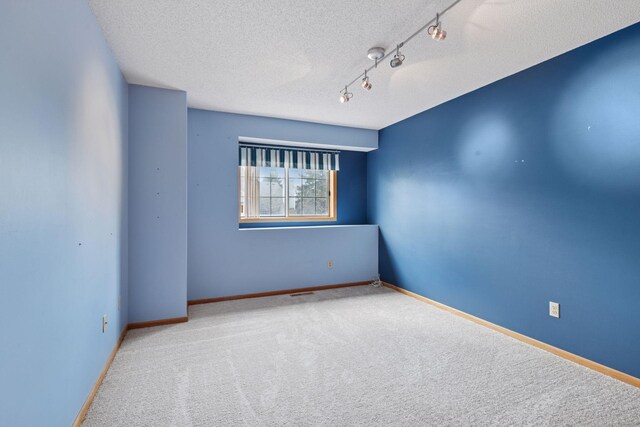 empty room featuring baseboards, carpet flooring, and a textured ceiling