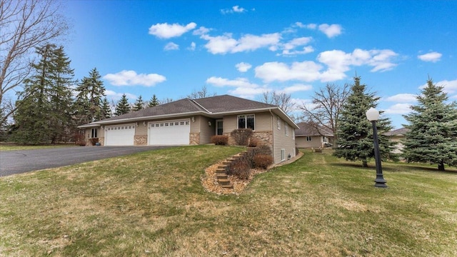 ranch-style house with an attached garage, a front yard, and aphalt driveway