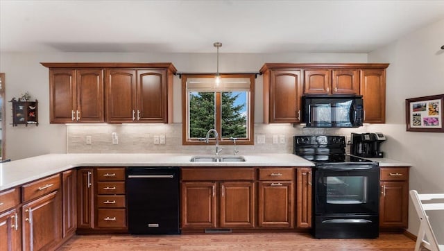 kitchen with a sink, backsplash, black appliances, and light wood-style flooring