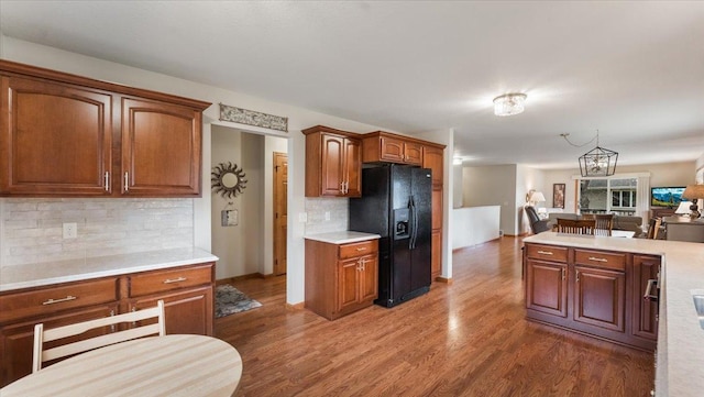 kitchen featuring wood finished floors, open floor plan, light countertops, tasteful backsplash, and black fridge