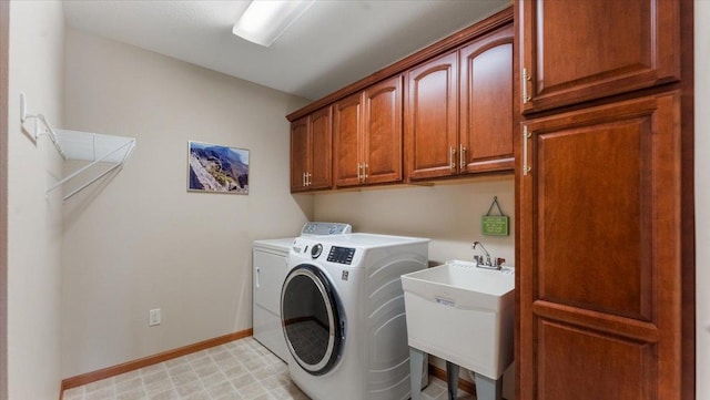 clothes washing area with a sink, baseboards, cabinet space, and independent washer and dryer