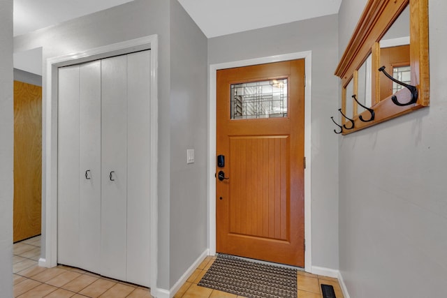 foyer featuring baseboards, light tile patterned floors, and visible vents