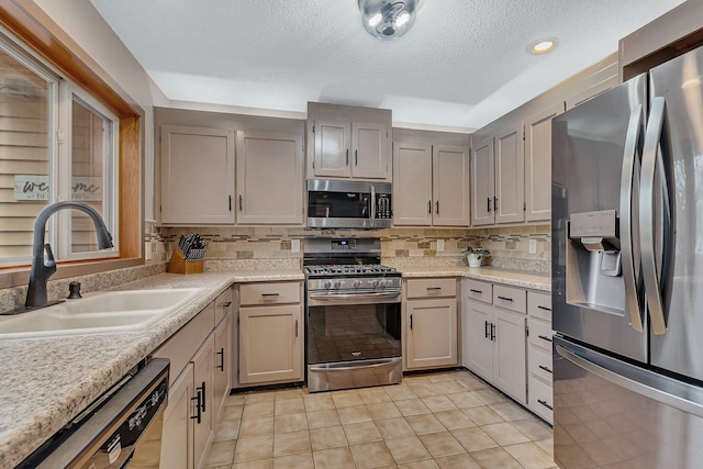 kitchen featuring a sink, light countertops, stainless steel appliances, and light tile patterned flooring