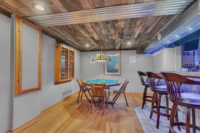 dining area featuring baseboards, bar area, wood ceiling, and wood finished floors