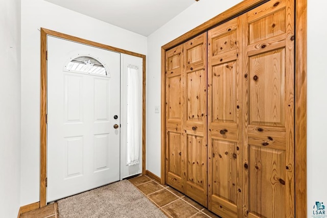 entrance foyer featuring baseboards and dark tile patterned flooring