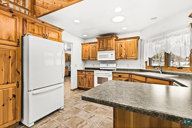 kitchen with a sink, dark countertops, white appliances, and brown cabinets