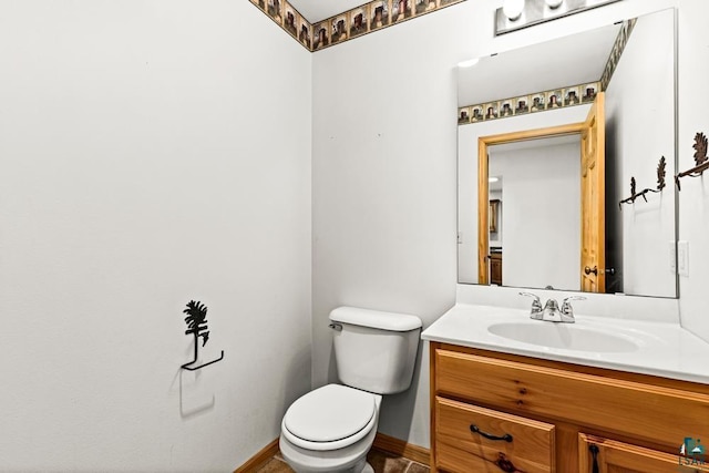 half bath with toilet, vanity, and baseboards