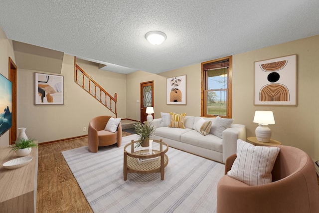 living room with baseboards, wood finished floors, a textured ceiling, and stairs