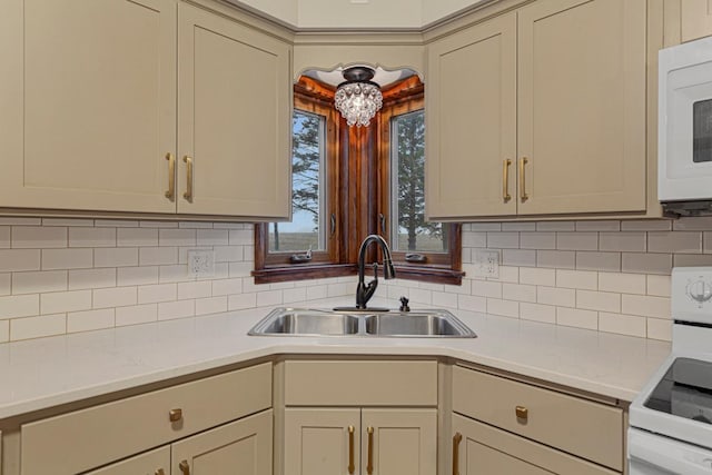 kitchen with backsplash, a sink, white appliances, and light countertops