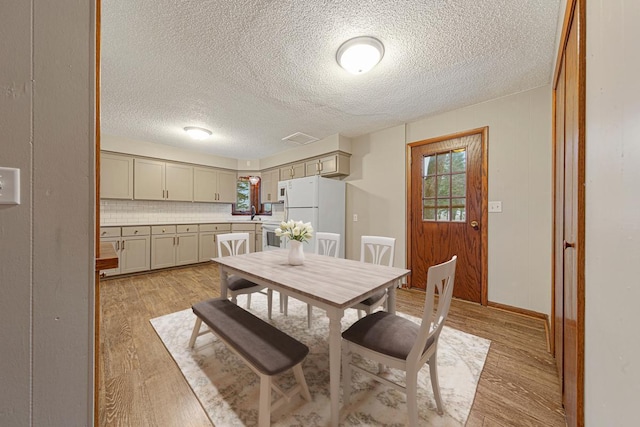 dining area featuring a healthy amount of sunlight, a textured ceiling, and light wood-type flooring