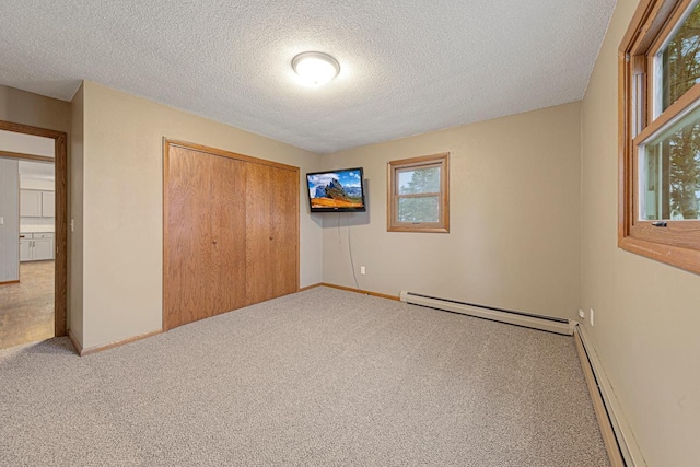 unfurnished bedroom with carpet floors, a textured ceiling, and baseboard heating