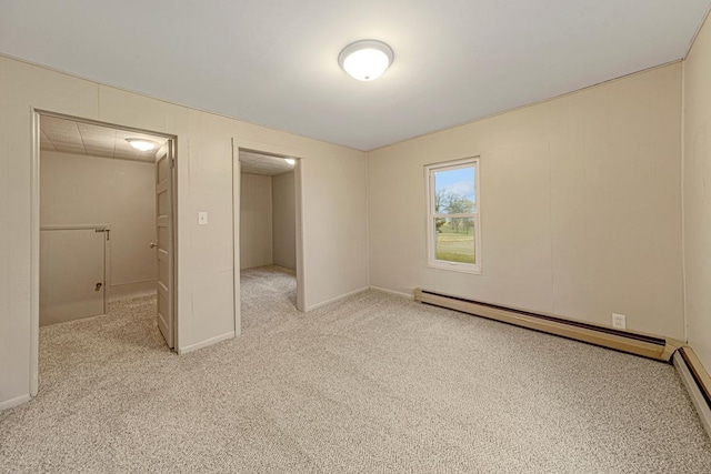 unfurnished bedroom featuring a spacious closet, baseboard heating, a baseboard heating unit, baseboards, and light colored carpet