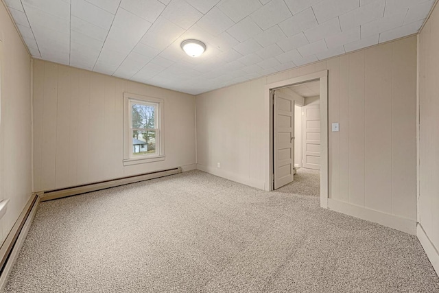 empty room featuring a baseboard heating unit and carpet