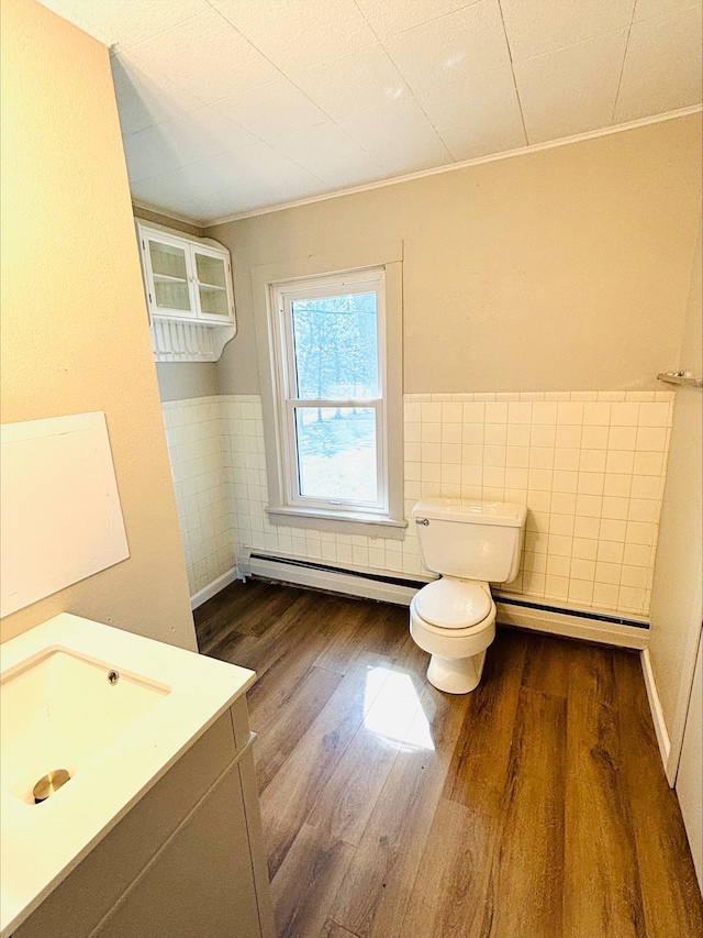 bathroom featuring a baseboard heating unit, toilet, crown molding, and wood finished floors