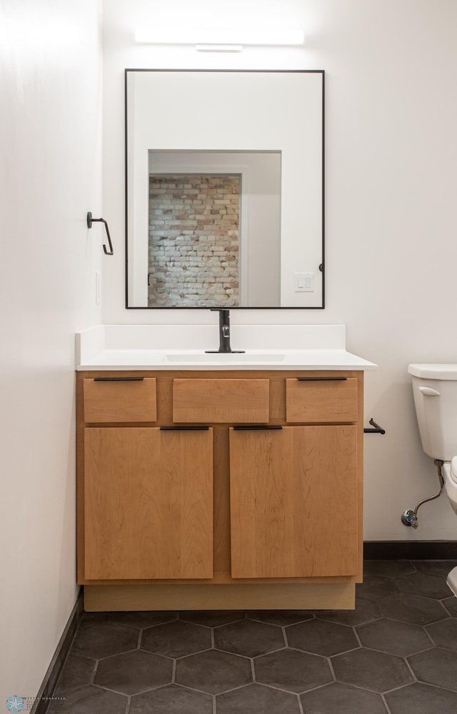bathroom with tile patterned flooring, toilet, vanity, and baseboards