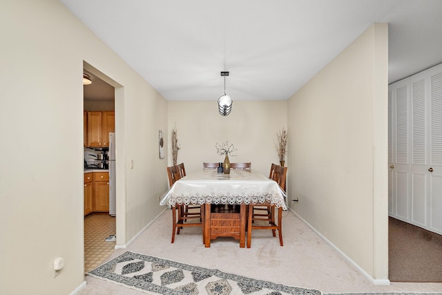 dining area featuring light carpet and baseboards