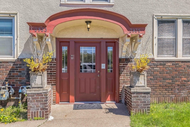 property entrance featuring stucco siding and brick siding