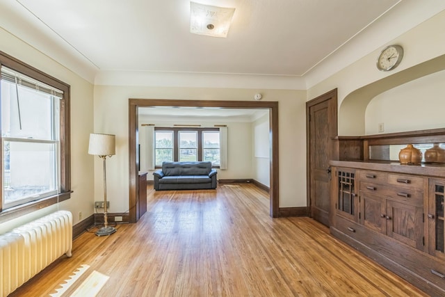 living area with radiator, light wood-style flooring, and baseboards
