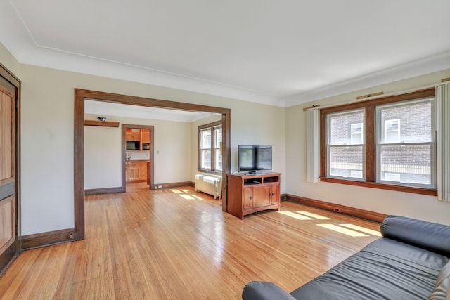 living room with radiator, baseboards, and light wood-style flooring