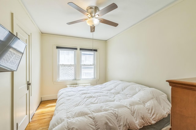 bedroom featuring light wood-type flooring, ornamental molding, ceiling fan, and baseboards