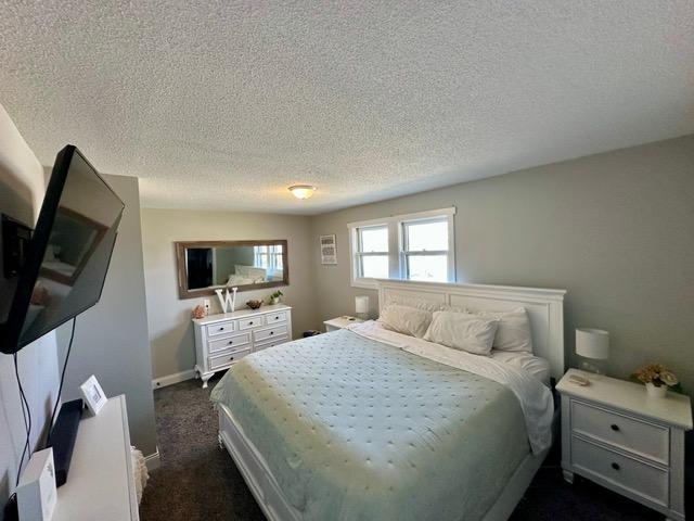 12787 Lumberjack Rd NW, Shevlin, MN 56676 - bedroom featuring a textured ceiling, dark colored carpet, and baseboards