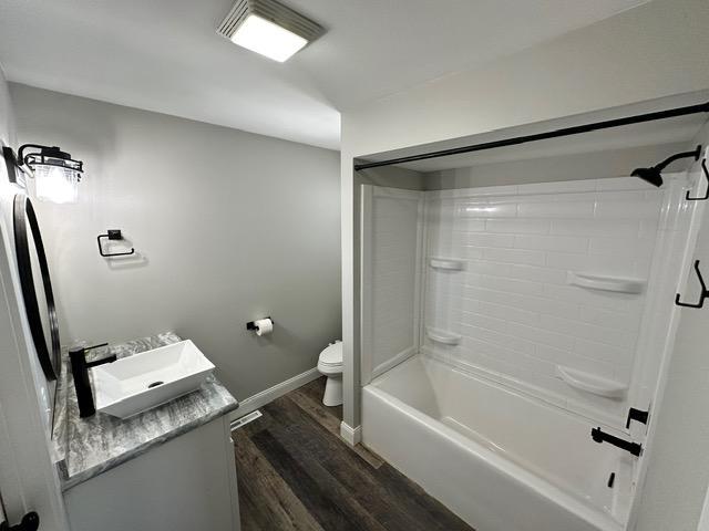 12787 Lumberjack Rd NW, Shevlin, MN 56676 - bathroom featuring wood finished floors, vanity, toilet, baseboards, and tub / shower combination