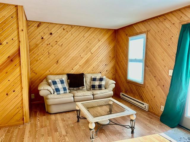 12787 Lumberjack Rd NW, Shevlin, MN 56676 - living area featuring a baseboard radiator, wood finished floors, and wooden walls