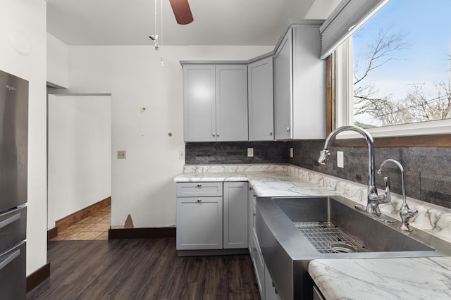 3301 Yosemite Ave S, Saint Louis Park, MN 55416 - kitchen with gray cabinets, a sink, tasteful backsplash, a ceiling fan, and light stone countertops