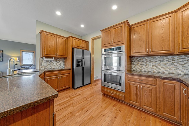 567 Forest Ln, Medford, MN 55049 - kitchen featuring tasteful backsplash, a sink, brown cabinetry, stainless steel appliances, and light wood-style flooring