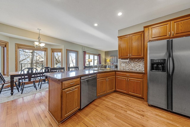 567 Forest Ln, Medford, MN 55049 - kitchen featuring brown cabinetry, a peninsula, a chandelier, and stainless steel appliances