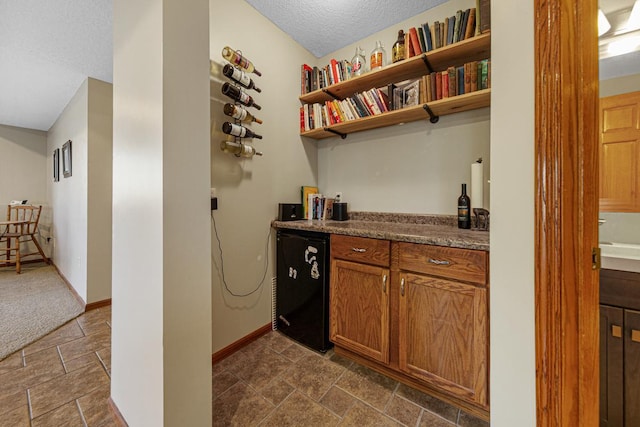 567 Forest Ln, Medford, MN 55049 - bar featuring a bar, stone finish flooring, baseboards, refrigerator, and a textured ceiling