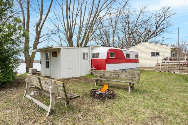 view of yard with a water view, an outbuilding, and an outdoor fire pit