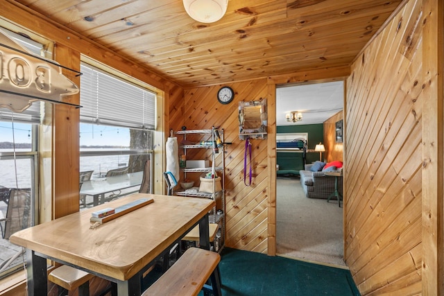 dining room featuring wood ceiling, carpet floors, and wood walls