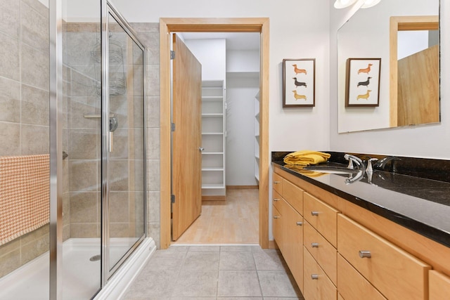 3707 Grand Way Unit 101, Saint Louis Park, MN 55416 - full bathroom with a shower stall, vanity, a walk in closet, and tile patterned floors