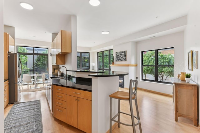 3707 Grand Way Unit 101, Saint Louis Park, MN 55416 - kitchen with a sink, freestanding refrigerator, light wood-style flooring, a kitchen breakfast bar, and a peninsula
