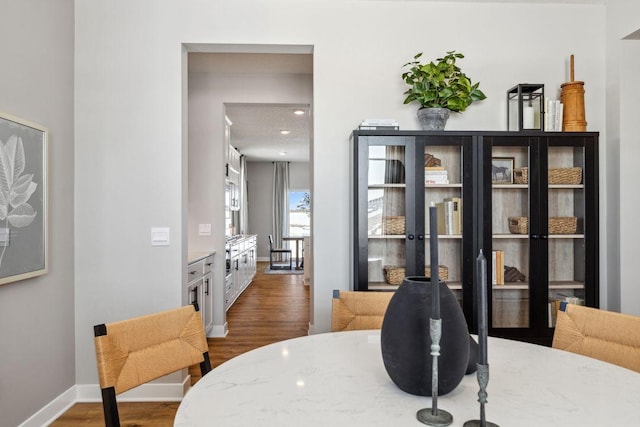 dining space featuring baseboards and dark wood-type flooring