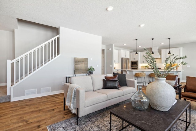 living area featuring stairway, recessed lighting, wood finished floors, and visible vents