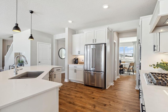 kitchen with light countertops, white cabinets, a sink, dark wood finished floors, and stainless steel appliances
