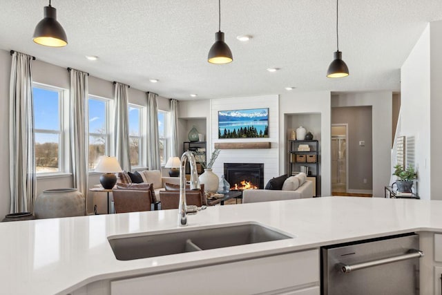 kitchen with a sink, light countertops, a textured ceiling, and dishwasher