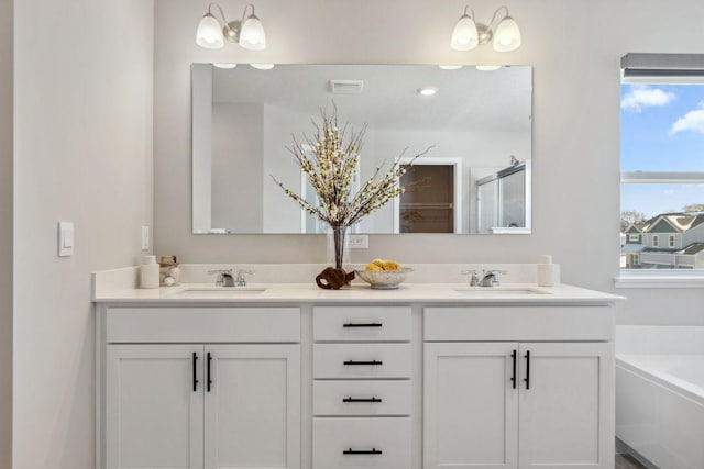 bathroom with a sink, a bath, a stall shower, and double vanity