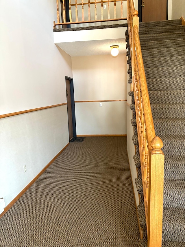 staircase featuring baseboards and carpet